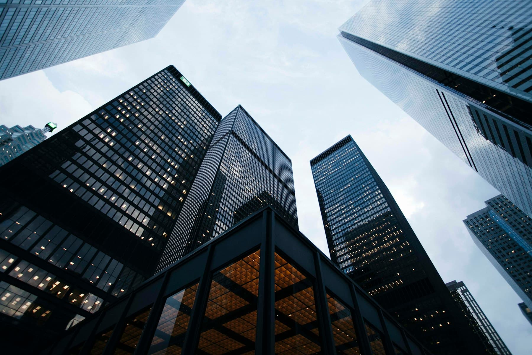 Looking upward between the intersecting lines of glass and steel buildings
